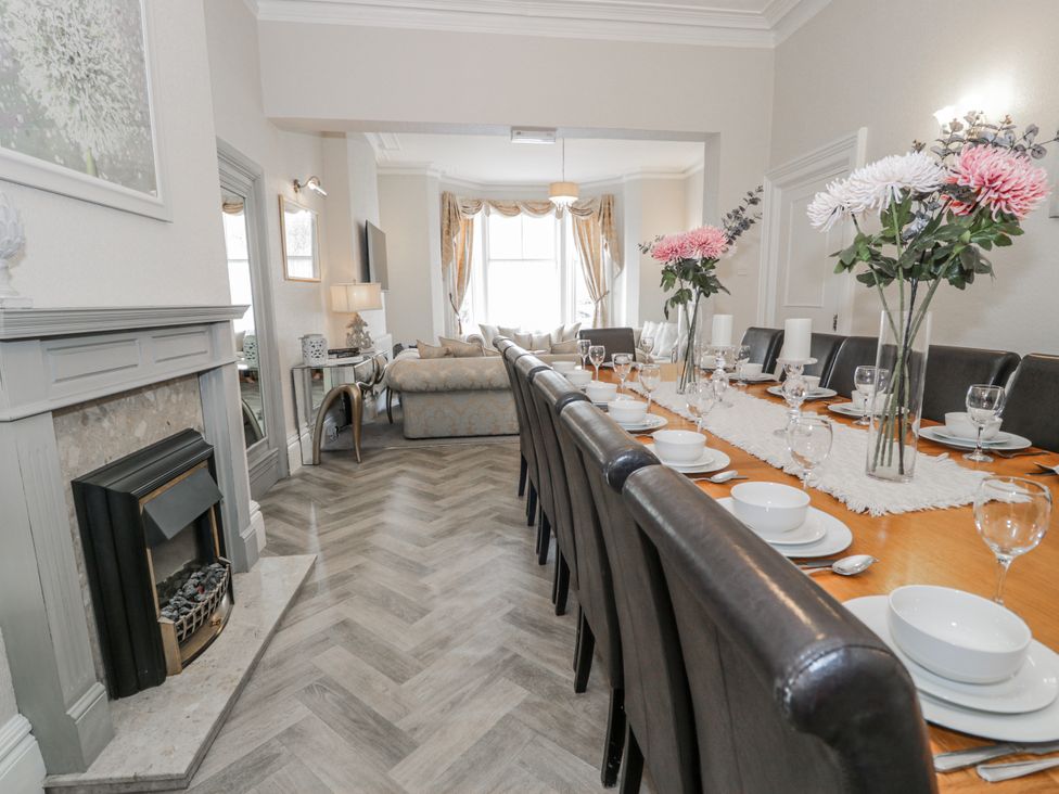 A dining room with a long table set for meals at The Keep in Llandudno