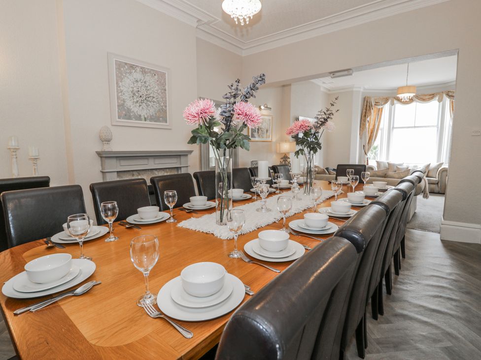 A dining room with a long table set for a meal at The Keep in Llandudno