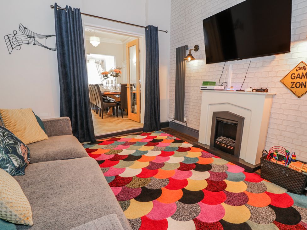 A living room featuring a sofa, television, and fireplace at The Keep in Llandudno