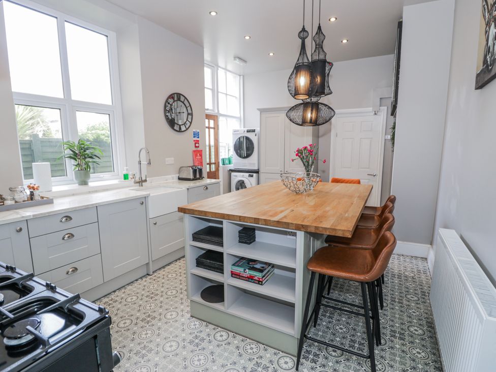 A kitchen with a large countertop and bar stools at The Keep in Llandudno
