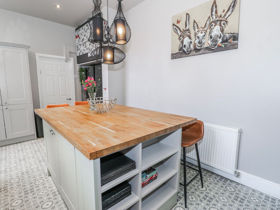 A kitchen with an island and stools at The Keep in Llandudno