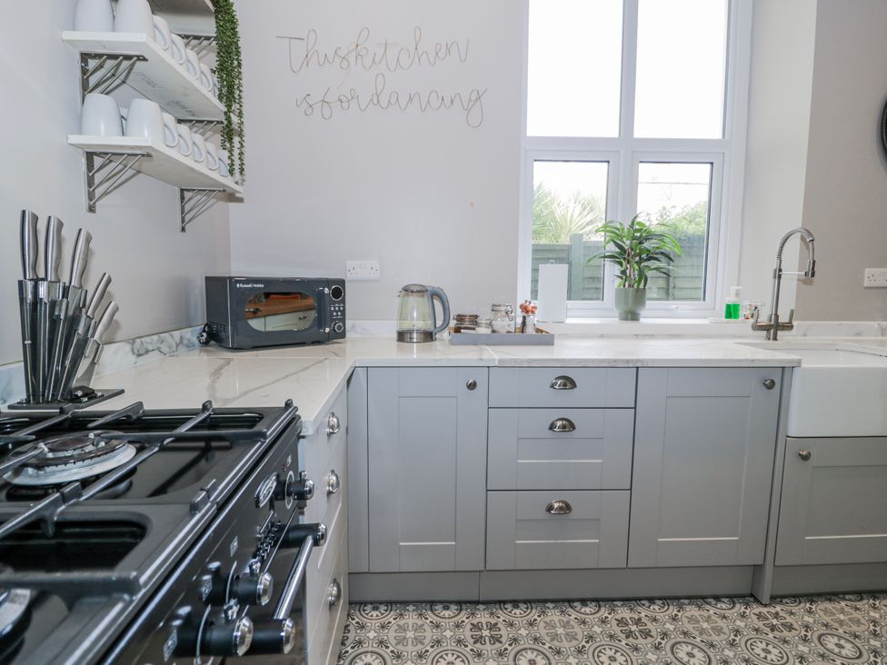 A kitchen with a gas stove and microwave at The Keep in Llandudno