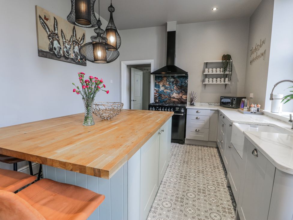 A kitchen with an island, oven, and sink at The Keep in Llandudno