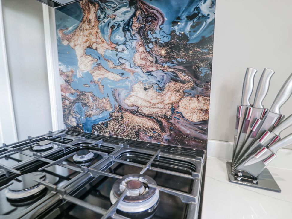 A kitchen with a gas stove and knife block at The Keep in Llandudno