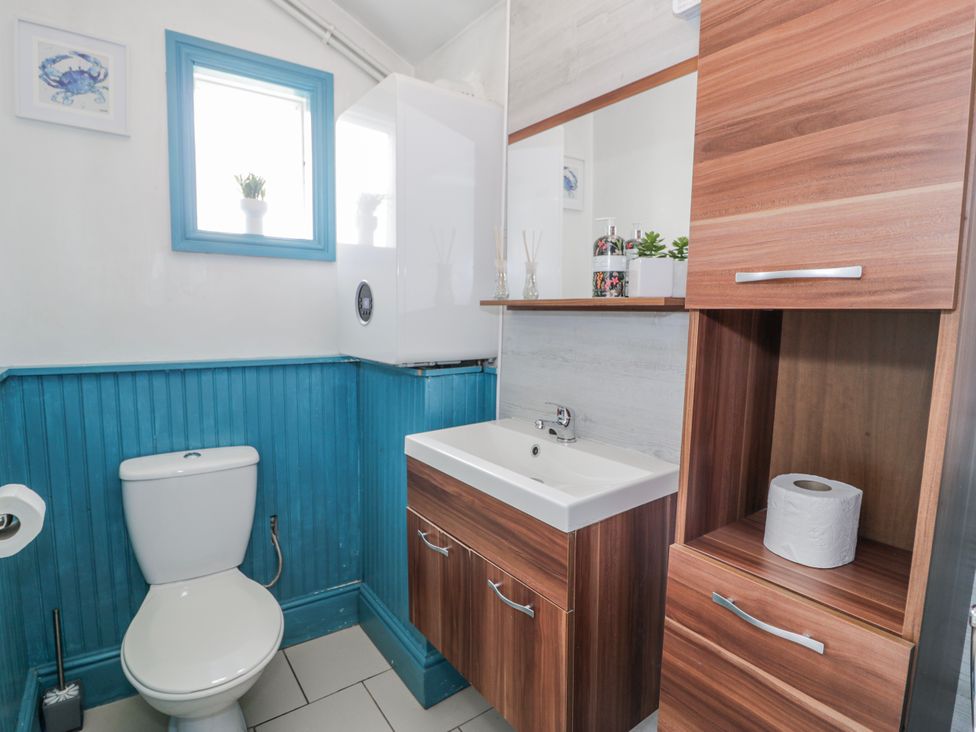 A bathroom with a sink, toilet, and shelving at The Keep in Llandudno