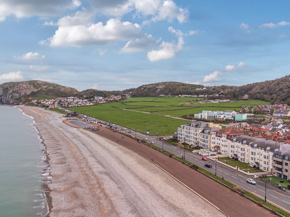 A beach with water and buildings near the shoreline at The Keep in Llandudno