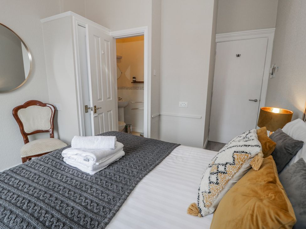 A bedroom with a bed and chair at The Keep in Llandudno