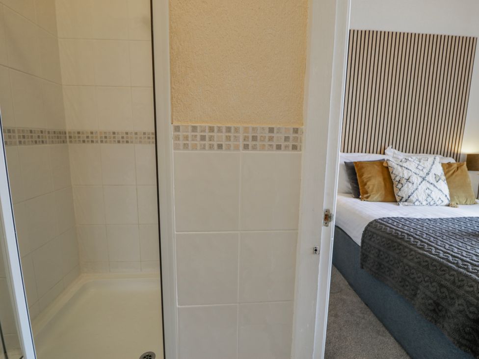 A bathroom with a shower and a view into a bedroom at The Keep in Llandudno