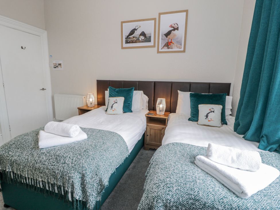 A bedroom with twin beds and wall art at The Keep in Llandudno