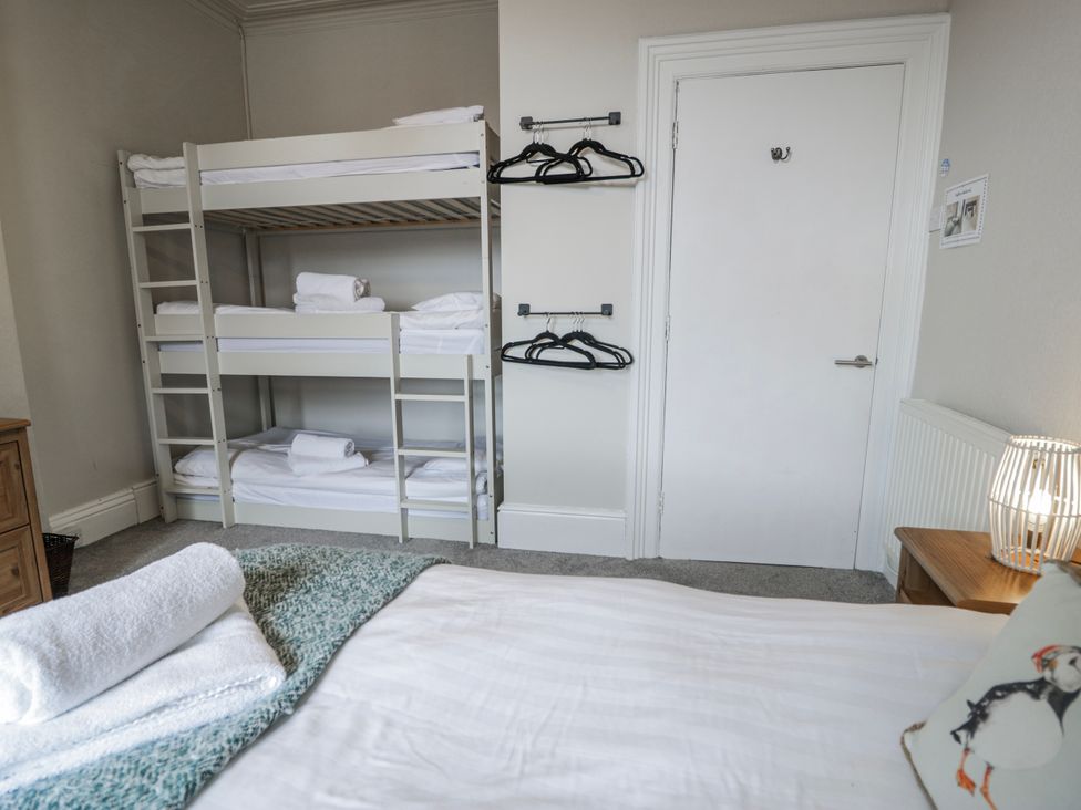 A bedroom with a bunk bed and storage at The Keep in Llandudno