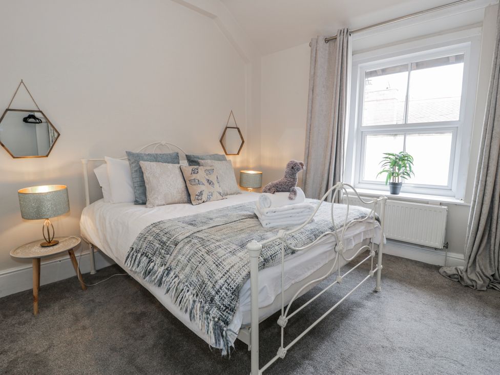 A bedroom with a bed, nightstand, and window at The Keep in Llandudno