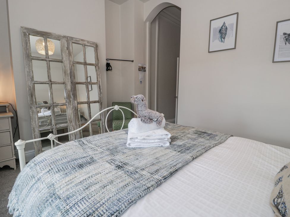 A bedroom with a bed, towels, and a mirror at The Keep in Llandudno