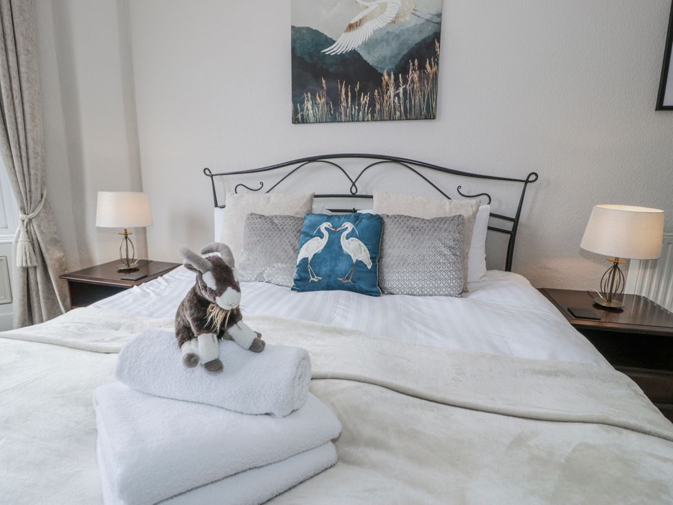 A bedroom with a bed, nightstand, lamp, and towels at The Keep in Llandudno