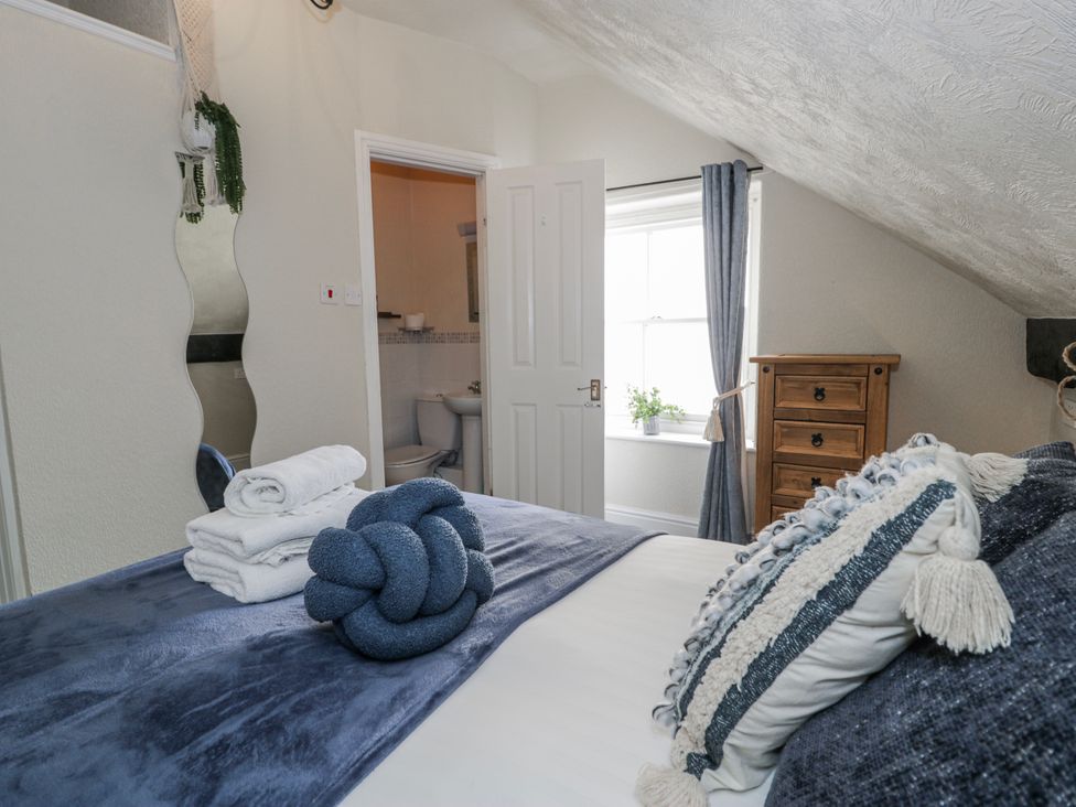 A bedroom with a bed and bathroom door at The Keep in Llandudno