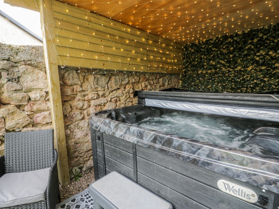 An outdoor area with a hot tub and seating at The Keep in Llandudno