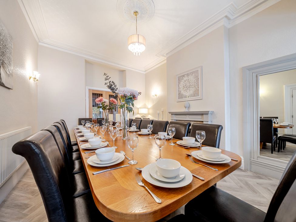 A dining room with a long table set for dinner at The Keep in Llandudno
