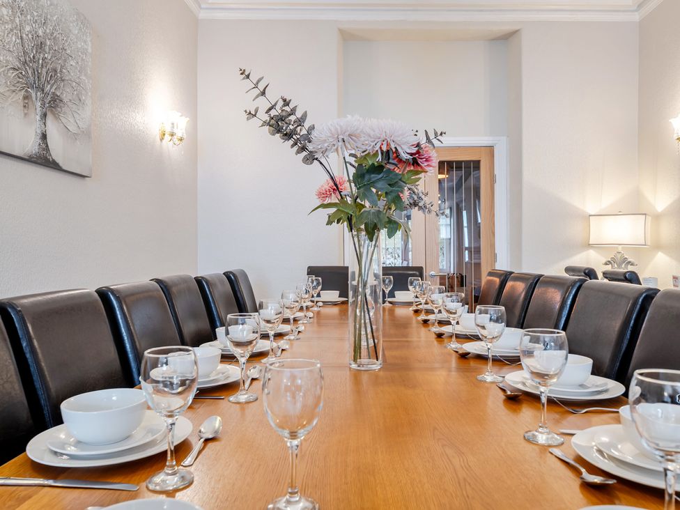 A dining room with a long table set for a meal at The Keep in Llandudno