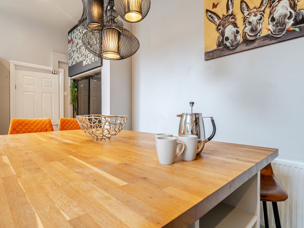 A dining room with a wooden table and kitchenware at The Keep in Llandudno