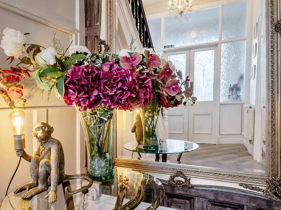 A hallway with flowers in a vase and a monkey statue at The Keep in Llandudno