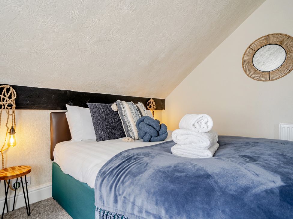 A bedroom with a bed, pillows, and towels at The Keep in Llandudno