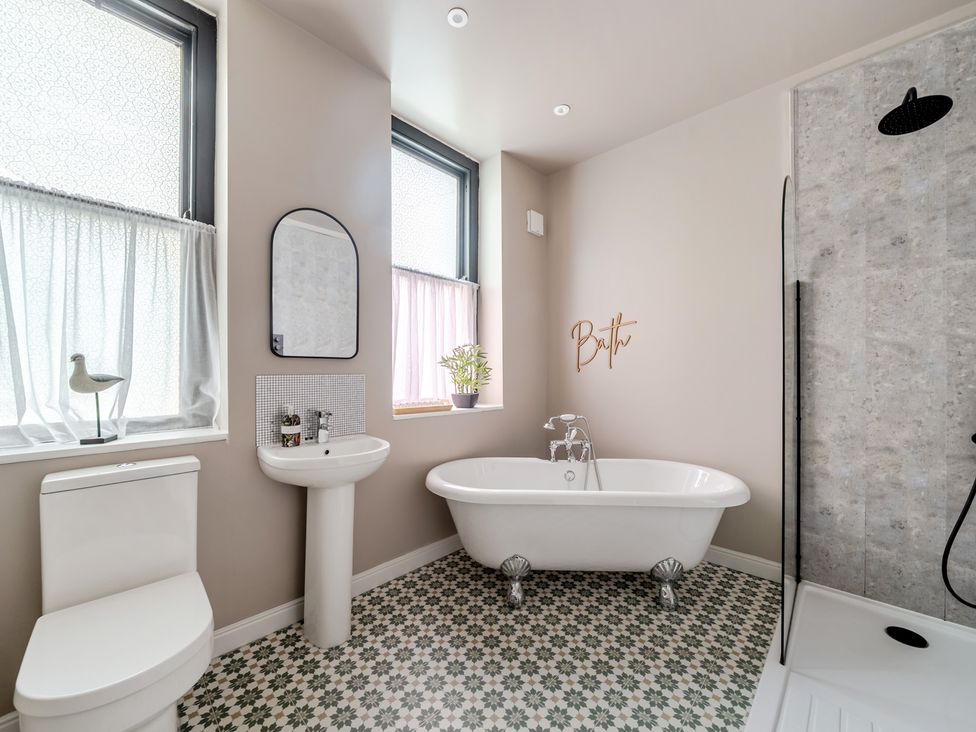 A bathroom with a bathtub, toilet, sink and shower at The Keep in Llandudno