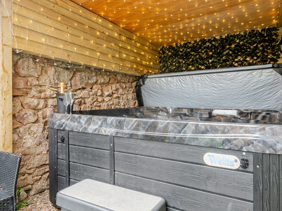 A hot tub with glasses and a bottle in an outdoor area at The Keep in Llandudno