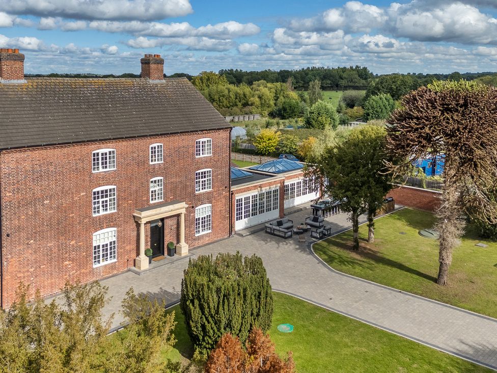 A brick building with a patio and outdoor seating area at Otherton Hall Penkridge