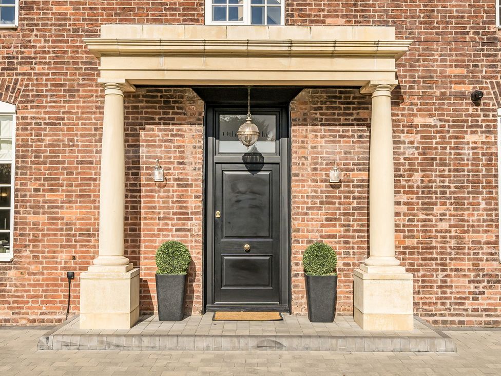 An entryway with a black front door and columns at Otherton Hall Penkridge