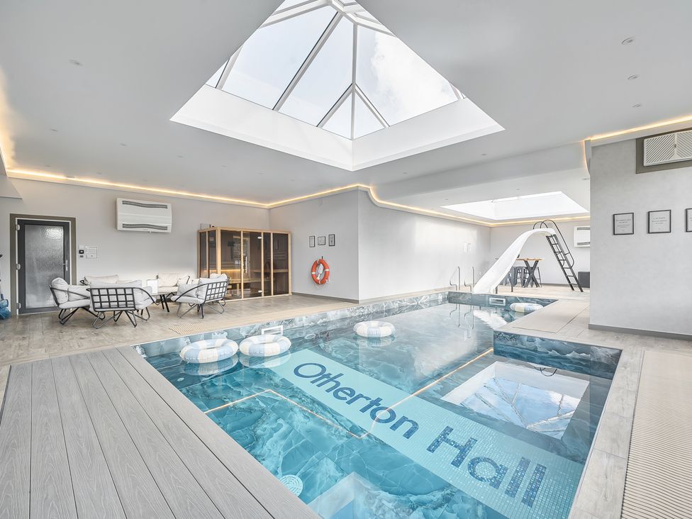 An indoor pool area with skylight and lounge chairs at Otherton Hall in Penkridge