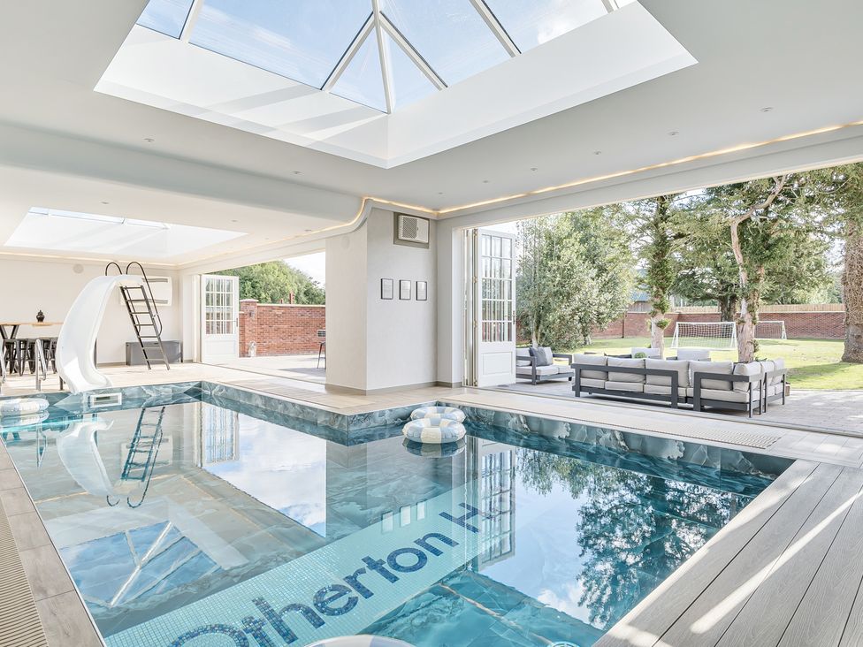 An indoor pool with a slide and outdoor seating at Otherton Hall Penkridge