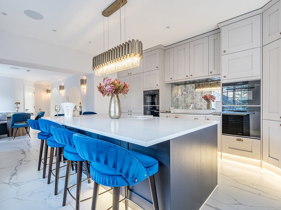 A kitchen with blue bar stools and a marble island at Otherton Hall Penkridge