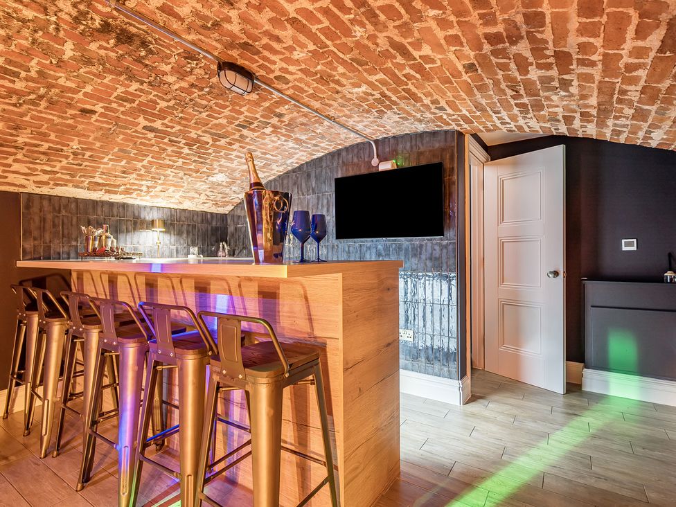 A bar area with stools and a television at Otherton Hall Penkridge