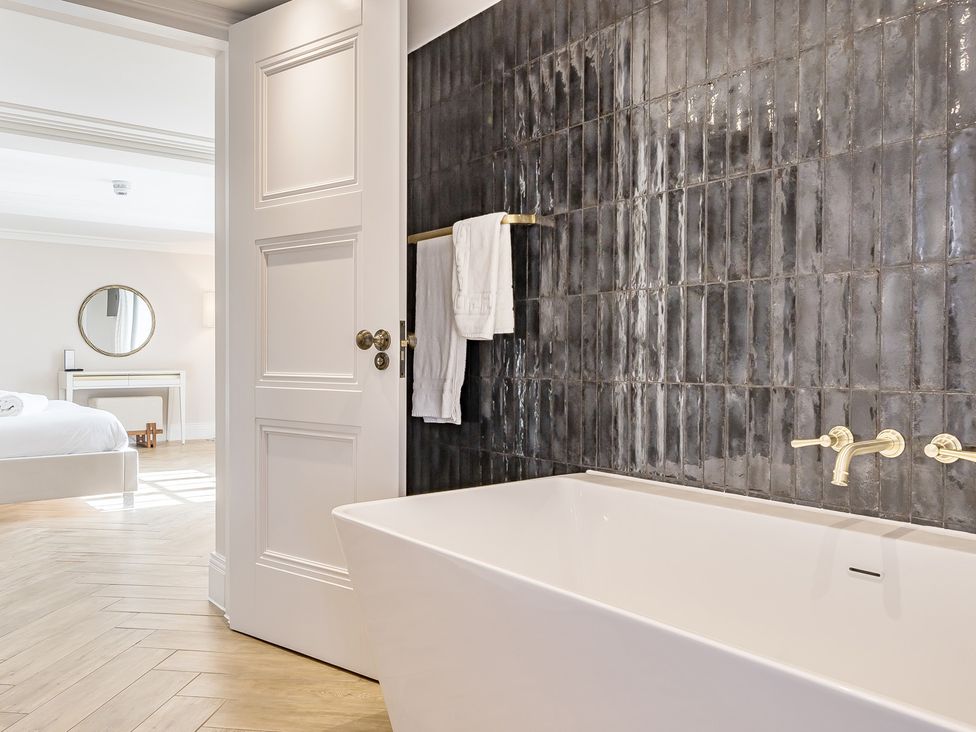 A bathroom with a bathtub and towels at Otherton Hall in Penkridge