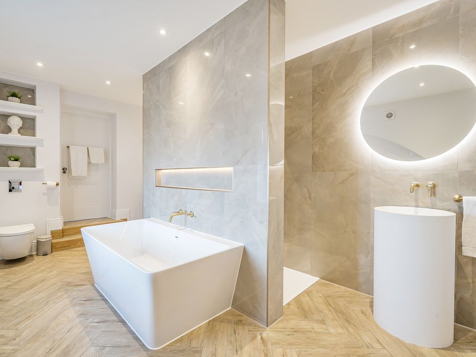 A bathroom with a bathtub, toilet, sink, and mirror at Otherton Hall Penkridge
