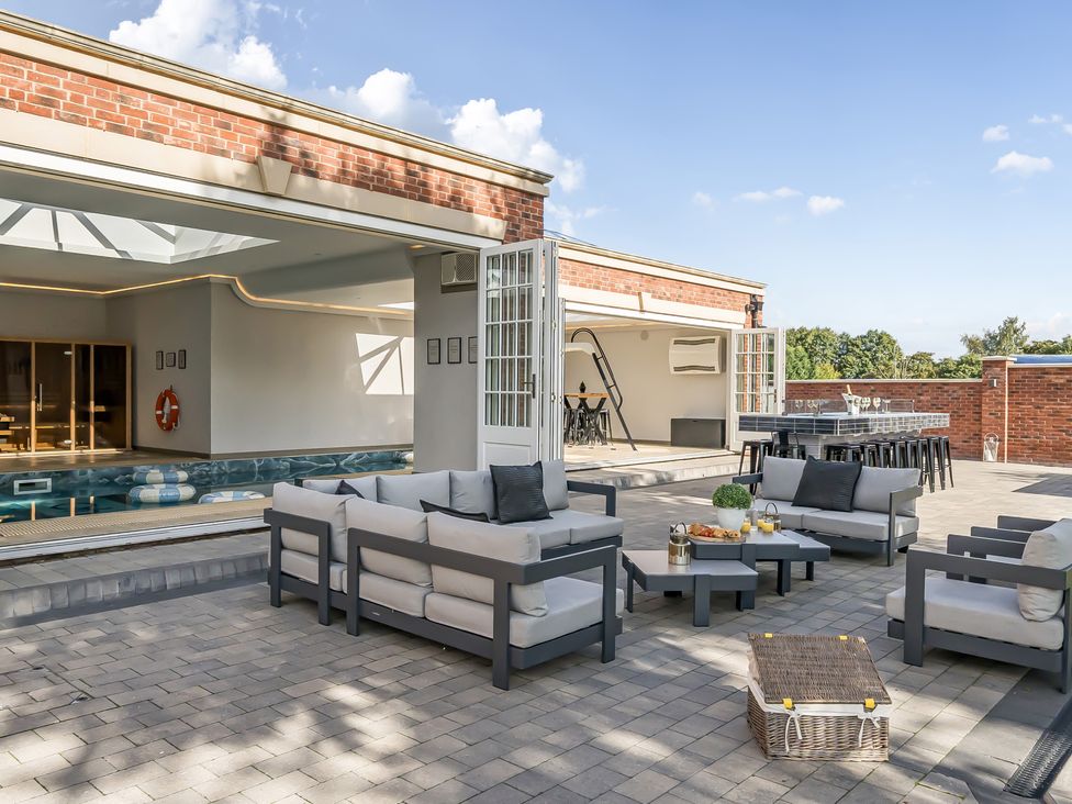 An outdoor patio with seating and a swimming pool at Otherton Hall in Penkridge