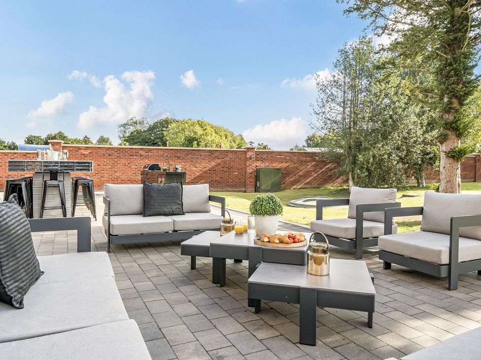 An outdoor seating area with cushions and a dining table at Otherton Hall in Penkridge