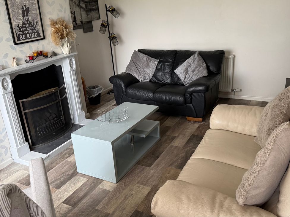 A living room with a fireplace and sofas at Bungalow by the Sea in Cleveleys