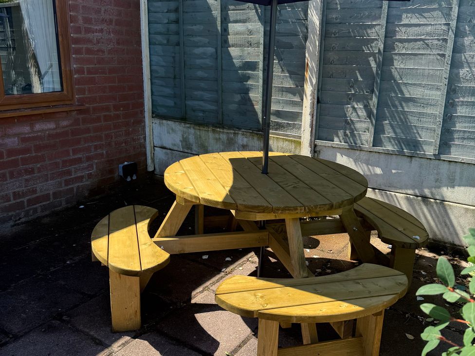 A wooden table with benches and an umbrella in an outdoor area at Bungalow by the Sea Cleveleys