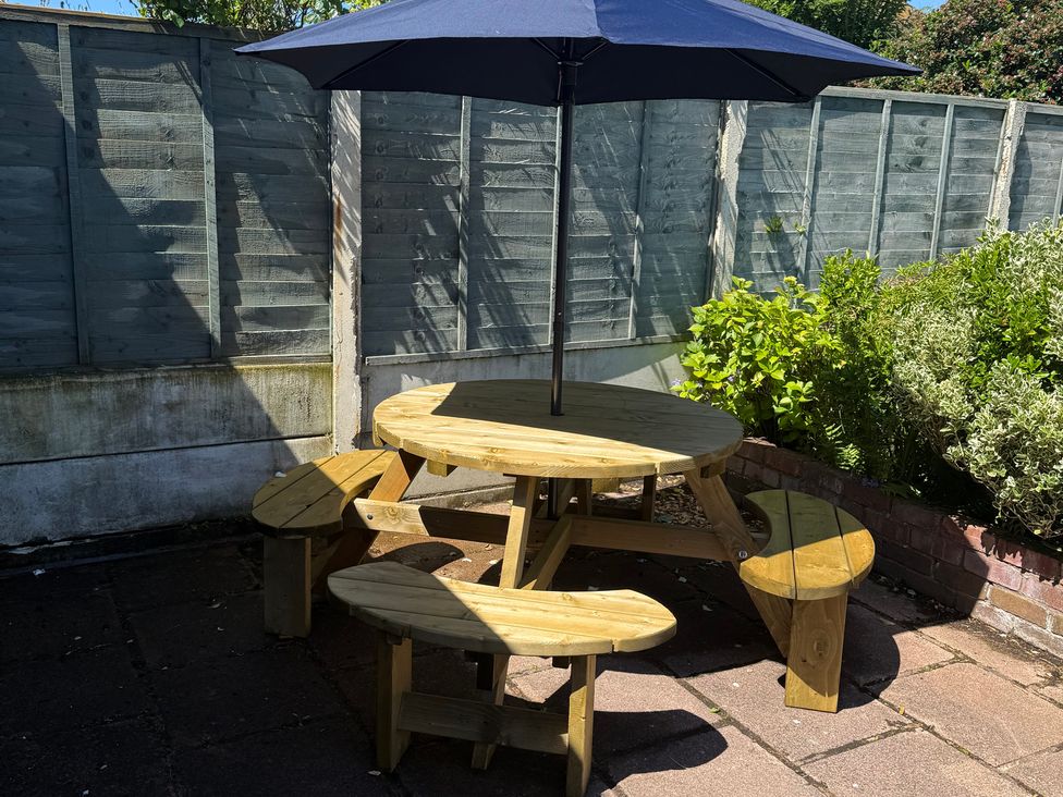 A garden with a round table and chairs under an umbrella at Bungalow by the Sea Cleveleys