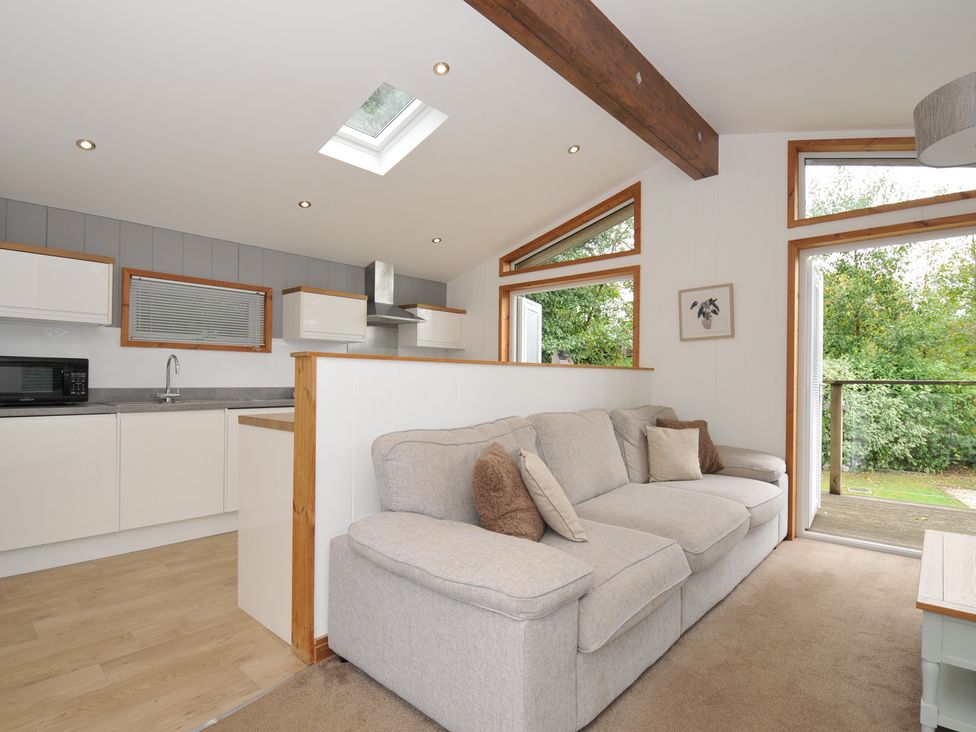 A living room with a sofa and kitchen area at 3 Southern Place in Dobwalls