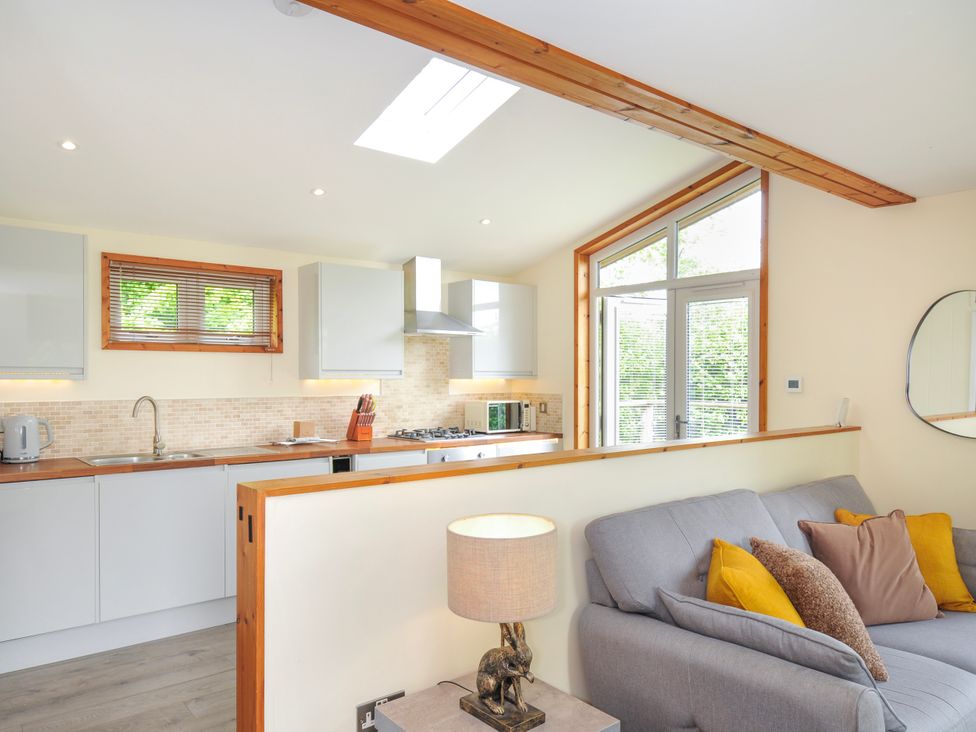 A living room with a kitchen area and a sofa at 5 Faraway Fields in Dobwalls