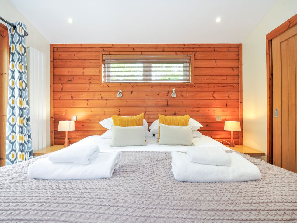 A bedroom with a double bed and wooden wall at 5 Faraway Fields in Dobwalls
