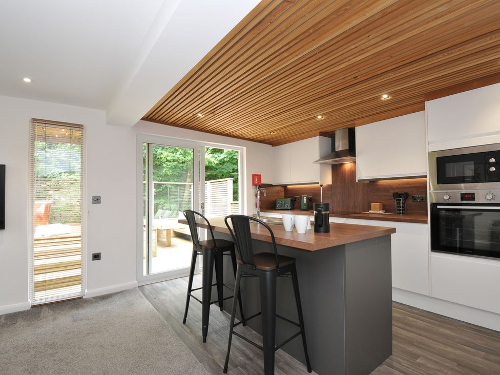 A kitchen with bar stools and appliances at 24 Meadow Retreat in Dobwalls