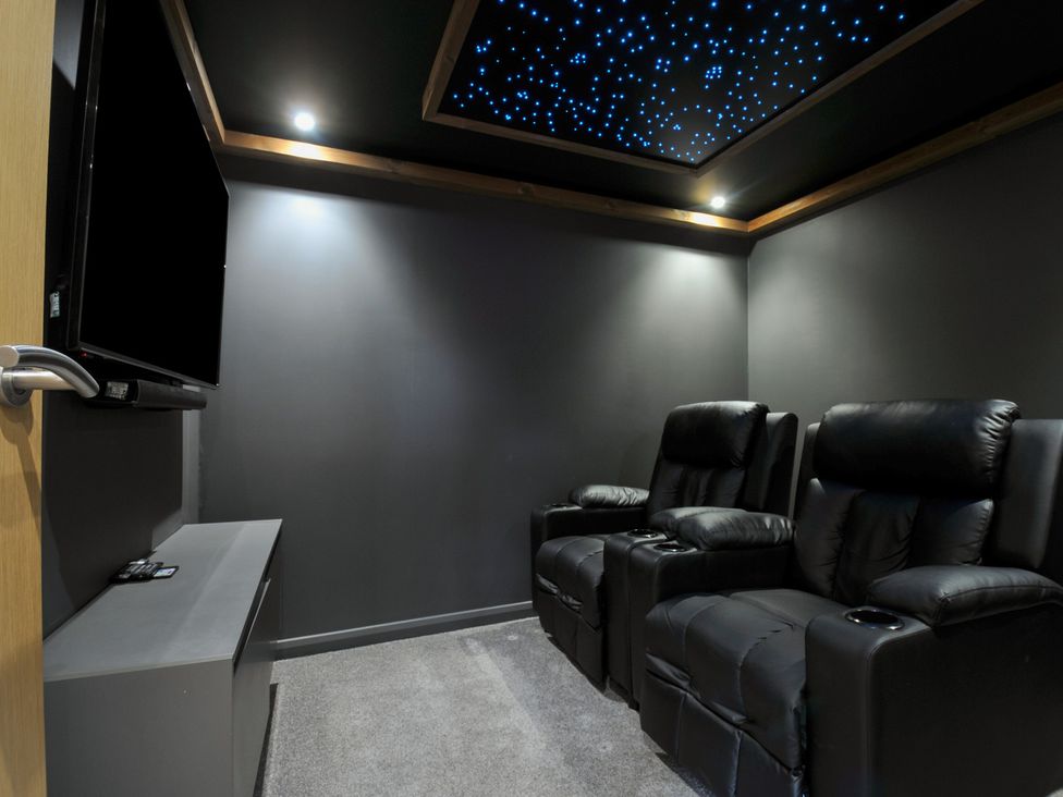 A home theater with black recliner chairs and a television at 24 Meadow Retreat Dobwalls