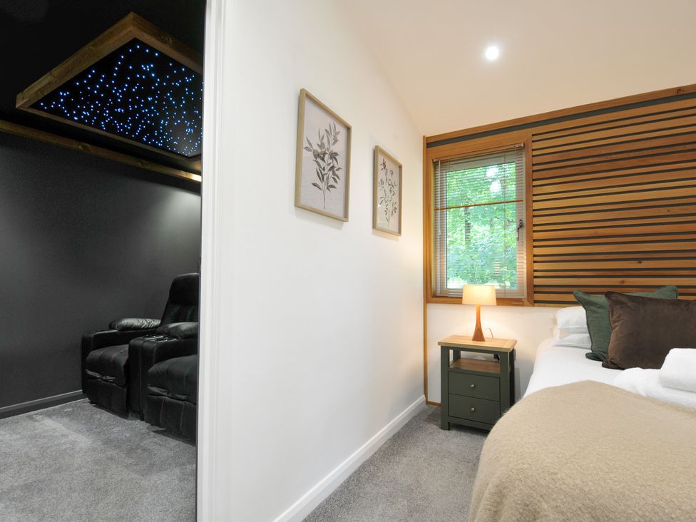 A bedroom with a bed, nightstand, and armchair at 24 Meadow Retreat in Dobwalls