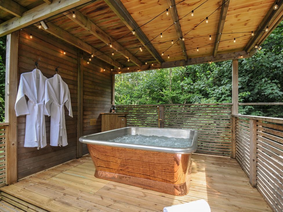 An outdoor spa area with a hot tub and robes at 24 Meadow Retreat in Dobwalls