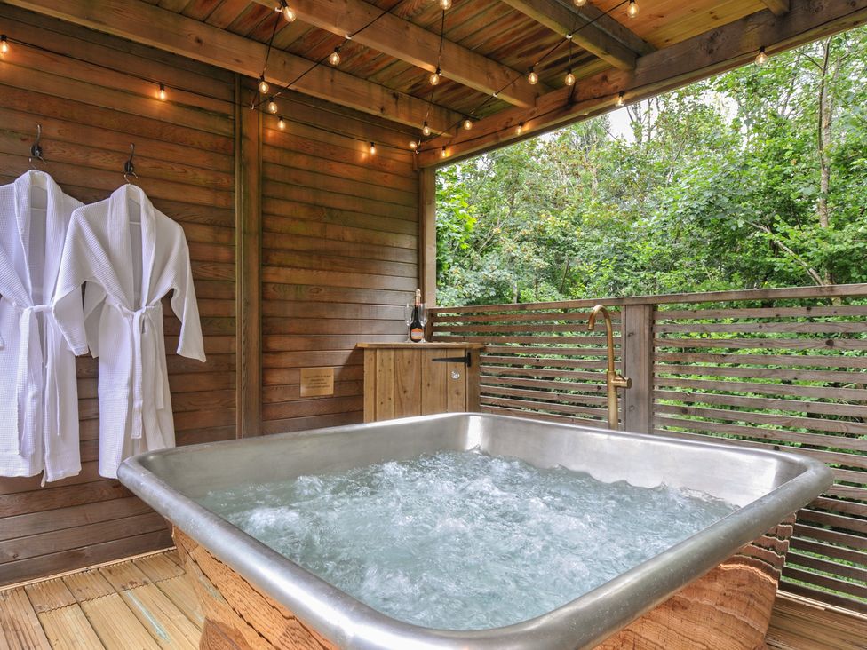 An outdoor spa area with a hot tub and wooden deck at 24 Meadow Retreat in Dobwalls