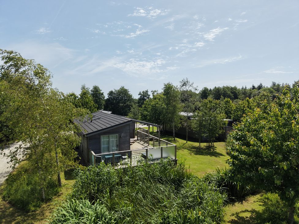 A house with a deck surrounded by trees and grass at 11 Meadow Retreat in Dobwalls