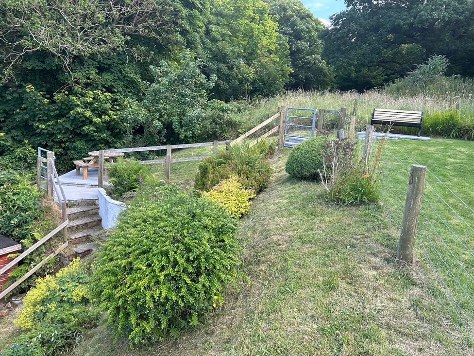 A garden with a path, plants, stairs, and a bench at Delfryn, Newport