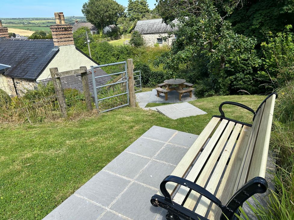 A garden with a bench, table, and chairs at Delfryn, Newport
